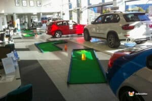 A car dealership featuring a fun golf course with putting greens and various cars on display.