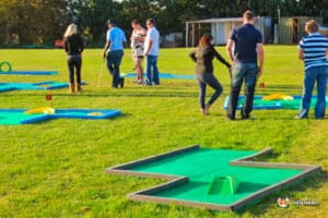 A group of friends enjoying a game of miniature golf on a vibrant green field with nine holes.