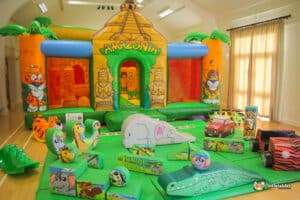 Colorful inflatable jungle-themed bounce house surrounded by soft play animal toys, creating a fun play area for children.