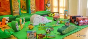 Colourful indoor play area filled with animal-themed soft play equipment, including slides, obstacles, and ride-on toys.