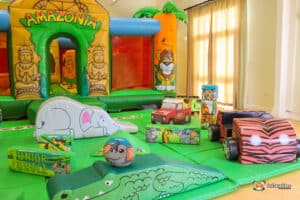 A colorful inflatable playground themed 'Amazonia,' featuring animal-shaped toys, cars, and vibrant decorations in a bright indoor space.