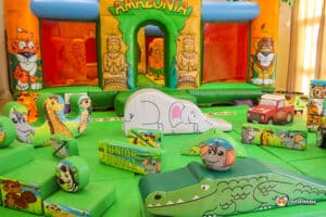 A colorful indoor jungle play area featuring a bouncy castle, soft inflatable animals, and vibrant obstacle shapes designed for children.