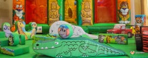 Colorful jungle-themed inflatable playground with cartoon animals, slides, and obstacles, perfect for young children to play and explore.