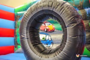 A tire sits in the center of a colorful bouncy castle, labeled "Auto Bouncer," inviting playful activities.