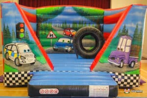 A fun bouncy castle in the shape of cars and a tire, branded as "Auto Bouncer," perfect for children's entertainment.