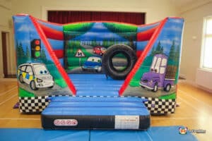 A lively bouncy castle featuring car designs and a tire, called "Auto Bouncer," designed for children's enjoyment.