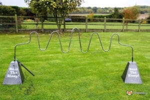 A metal wire maze titled "Beat The Bleep!" set up on a grassy lawn, designed for a fun challenge outdoors.