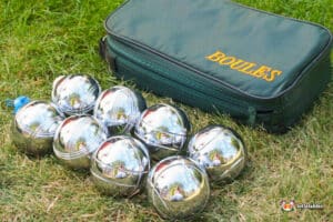 A group of silver boules balls resting on green grass, ready for a game of boules