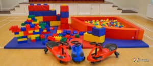Colorful play area featuring building blocks, a ball pit, and ride-on toys on a soft mat, perfect for children's playtime activities.
