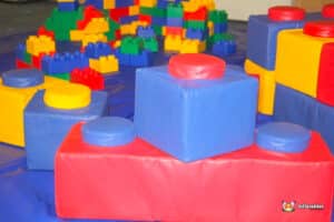 Colorful foam building blocks in red, blue, and yellow scattered on a blue mat, ideal for children's play and creativity.