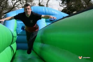 A man joyfully runs on an inflatable bungee run, showcasing excitement and energy.
