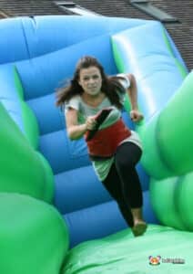 A woman energetically runs along an inflatable bungee run, highlighting the excitement of the game.