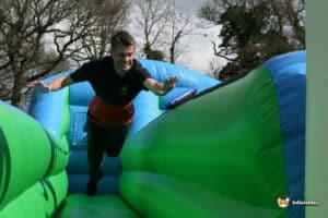 A man dashes down an inflatable bungee run, embodying the joy of outdoor play.