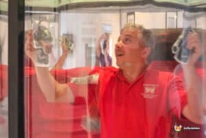 A man in a red shirt is excitedly holding a cash grabber game, showcasing the money inside for players to grab.