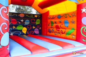 A vibrant, colorful bouncy castle interior with balloons, stars, and playful designs on the walls for children's entertainment.