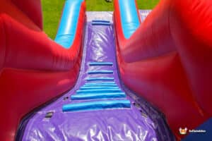 A colorful inflatable slide in purple and red, called the "Celebrations Slide," inviting children to slide and play.