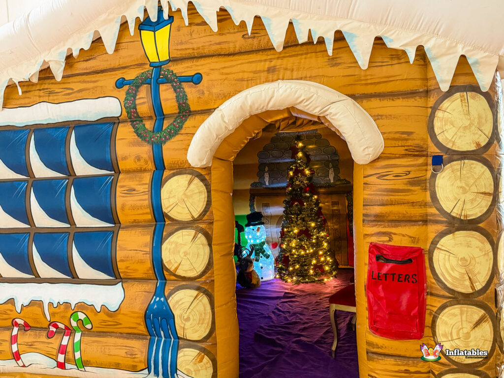 Close-up view of the grotto's entrance from the outside, with the curtains pulled back to reveal the bright, decorated Christmas tree and snowman figure inside.