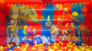 A colorful bouncy castle featuring a large inflatable ball pit, inviting children to play and enjoy a fun-filled experience.