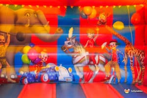 A vibrant bouncy castle designed with a circus theme, showcasing bright colors and fun patterns for kids to play on.