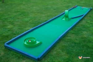 A lively miniature golf course scene with a bright green putting green, highlighting the "Crazy Hole in 1" challenge.