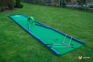 A fun miniature golf course displaying a green putting green with fun clubs for all ages.