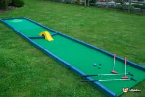 A cheerful miniature golf course with a green putting green, featuring the playful "Crazy Hole in 1" for golfers to enjoy.