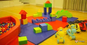 A vibrant play area featuring a large green and blue building, inviting children to explore and enjoy soft play activities.