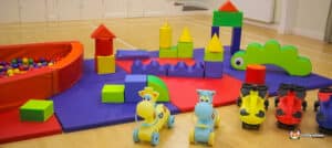 A cheerful play area featuring a large green and blue structure, designed for children to have fun with soft play.