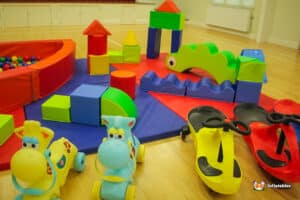 A playful scene with a large green and blue building in a soft play area, encouraging kids to explore and create.