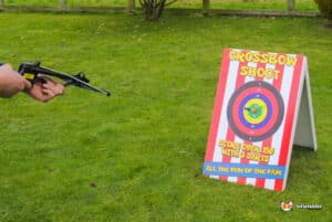 A man aiming a crossbow towards a target during a shooting challenge.