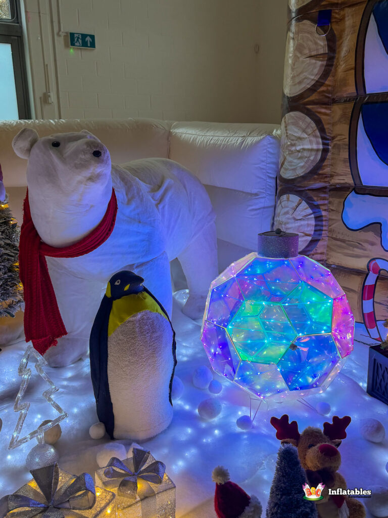 Close-up of the highly decorated winter scene outside the grotto, featuring a large polar bear with a red scarf, a penguin, and a prominent, color-changing, light-up faceted ornament.