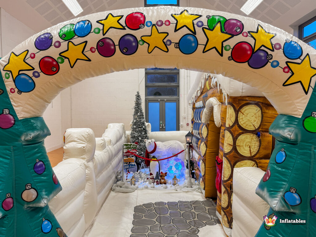 View looking through the large, decorated inflatable archway towards the winter scene, the light-up polar bear, and the entrance to the log cabin grotto.