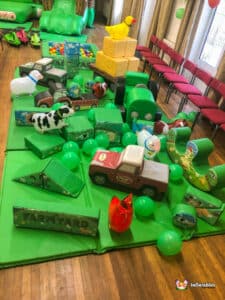 A vibrant play area at Deluxe Farm Soft Play, showcasing toys arranged on a soft green mat for children's playtime.