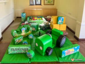 A play area at Deluxe Farm Soft Play, equipped with toys on a soft green mat, inviting children to engage in play.