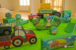 A colorful play area featuring toys and a green mat, designed for children at the Deluxe Farm Soft Play center.