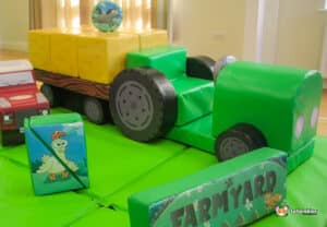 A vibrant farm-themed soft play area featuring a colorful tractor and playful farm animals for children to enjoy.
