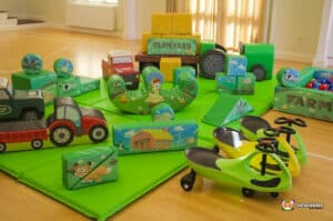 A colorful play area featuring various toys on a green mat, designed for children at the Deluxe Farm Soft Play.