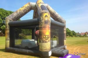 Colorful inflatable castle with a fire pit and a demolition wrecking ball, inviting fun and adventure in an outdoor setting.