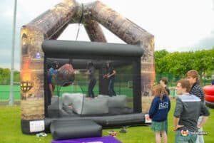 Two people are having fun on a large inflatable wrecking ball, showcasing their playful spirit in an outdoor environment.