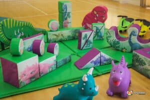 A cheerful play area with a dinosaur and assorted toys, creating a fun environment for kids to engage and play.