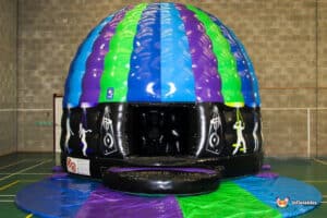 A colorful inflatable dome featuring blue, green, and purple stripes, with music-themed designs and a large opening at the front.