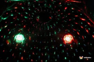 Colorful lights create a mesmerizing pattern in a dark, inflatable space, illuminated by green and red glowing effects.