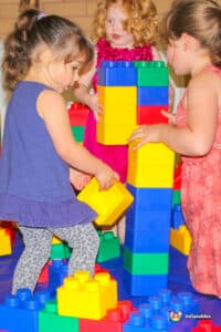 Three girls engaged in play, constructing with Edublocks and Lego blocks, showcasing creativity and teamwork.
