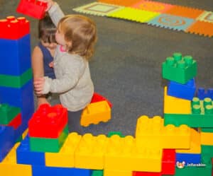 Two kids engaged in creative play with Edublocks Lego bricks, surrounded by colorful pieces.