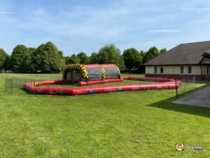 A vibrant inflatable obstacle course in a field, featuring a race track layout for participants to navigate and enjoy.