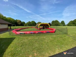 Go-karting in a park, highlighting colorful karts racing on a track with trees and a crowd of spectators nearby.