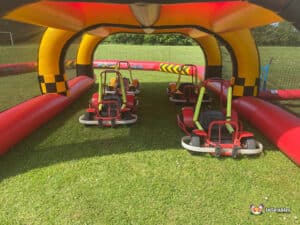 Go-kart racers navigating a track in a park, with lush greenery and enthusiastic spectators enjoying the thrilling event.