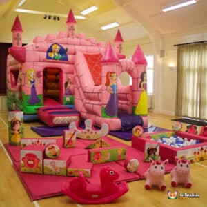 A pink enchanted-themed bouncy castle with matching soft play equipment designed for a princess-themed event.