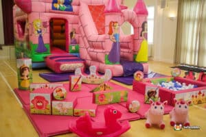 A whimsical pink bouncy castle featuring an enchanted theme, accompanied by soft play equipment for a princess celebration.