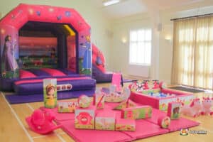 A vibrant play set featuring a bouncy castle, slide, and various toys, designed in a princess theme for children.